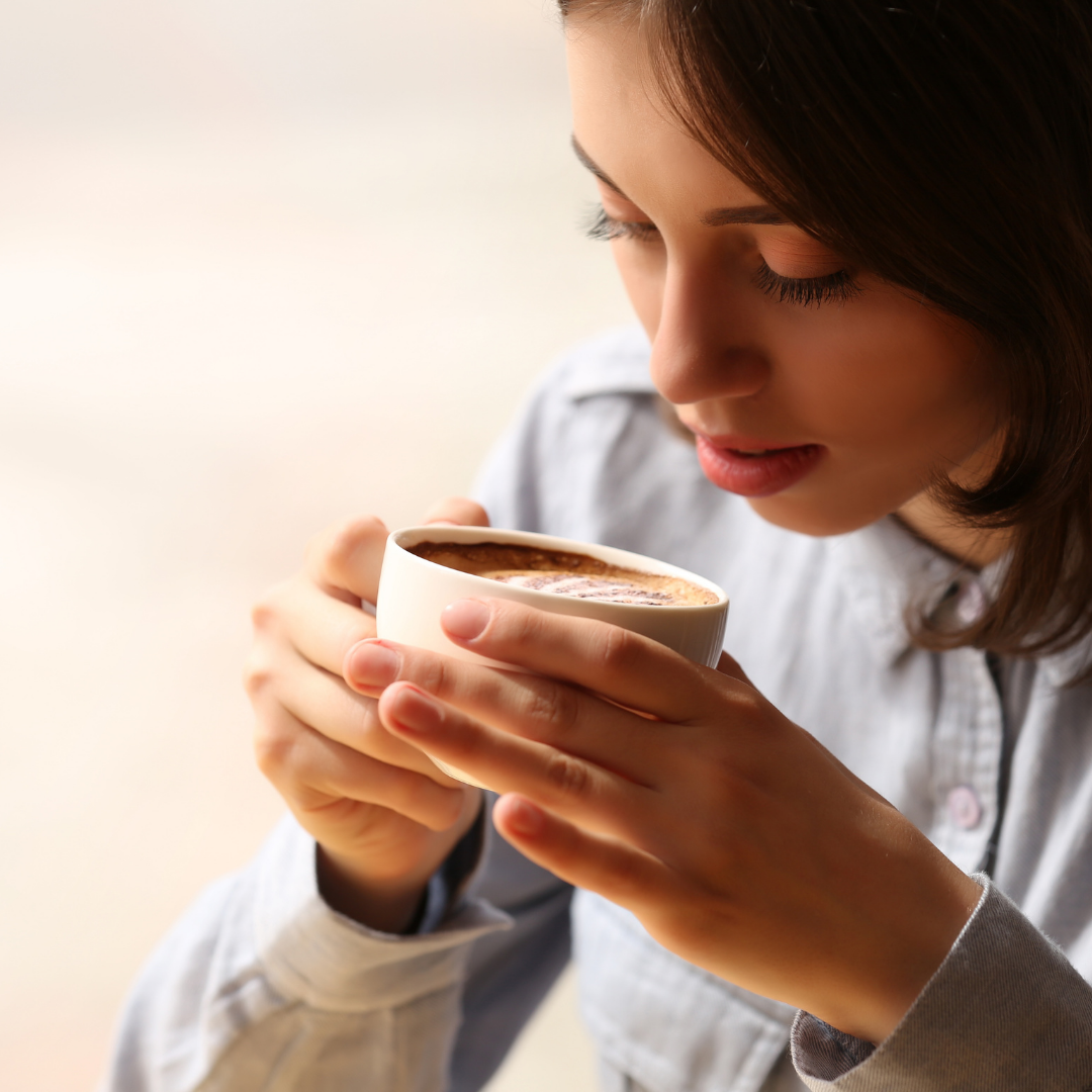 close up of woman holding coffee cup up to her mouth